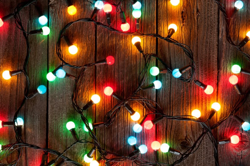 Home Holiday Lighting Electrical Tips. Christmas colorful lights on wooden table.