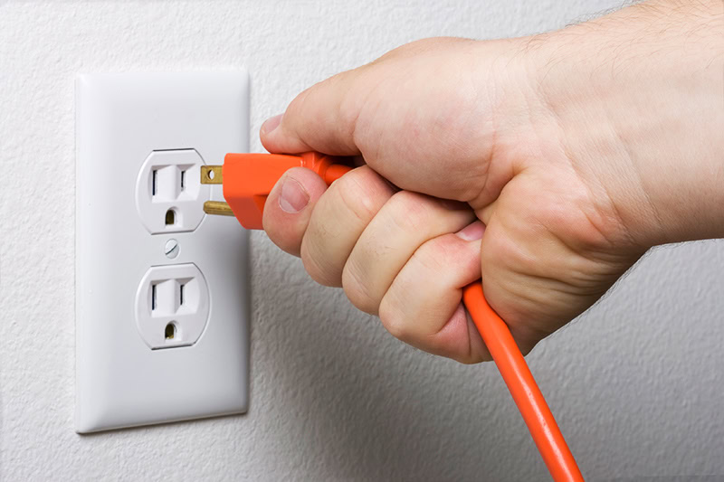 Will Unplugging Electrical Appliances Help Lower Your Electric Bill? Photo of someone unplugging an appliance.