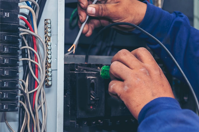 Upgrade Your Outdated Electrical Panel. Handyman working on an electrical panel.