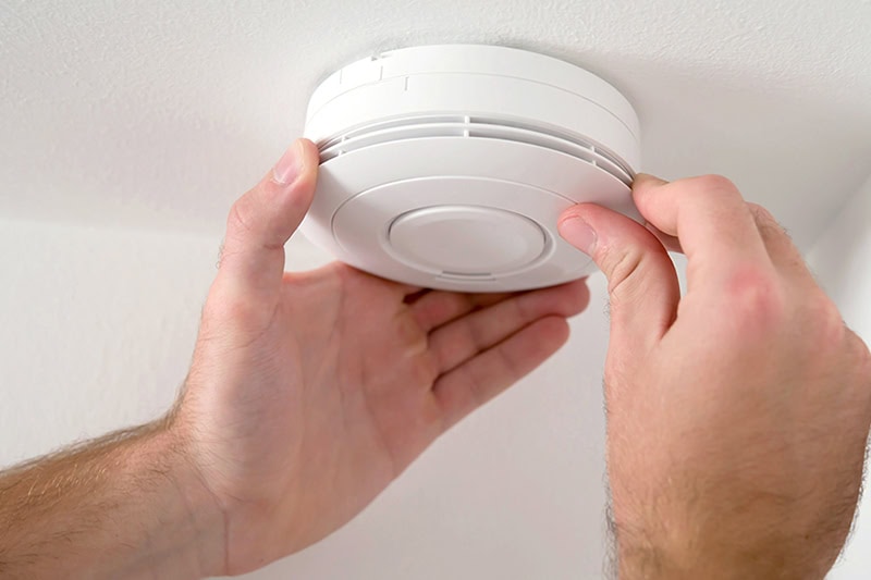Man installing smoke detector on ceiling of home.